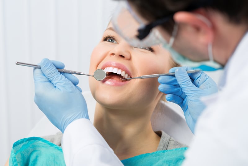 Dentist performing an oral exam with a mouth mirror