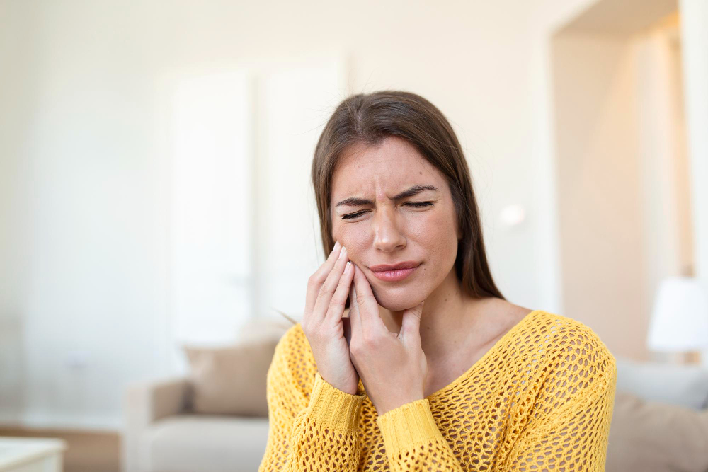 Woman holding her jaw from TMJ pain before treatment in Vancouver